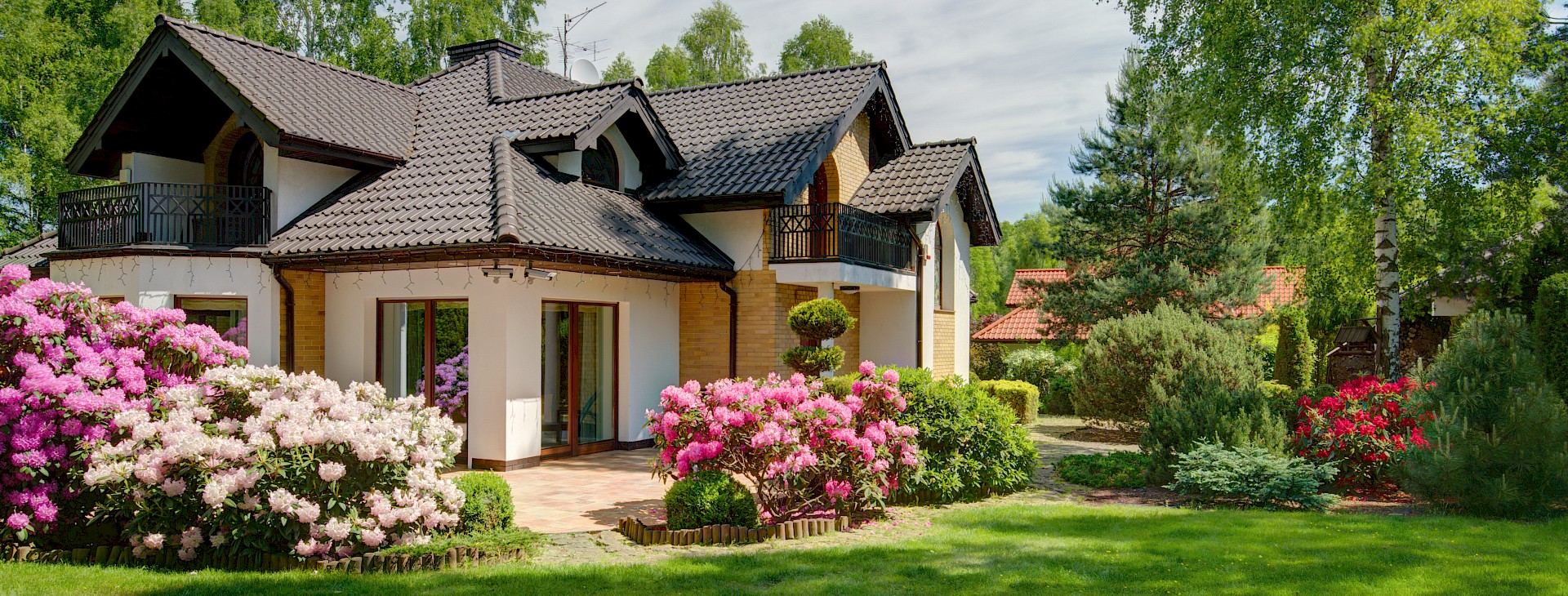 Modernes Haus mit gepflegtem Garten und blühenden Sträuchern.