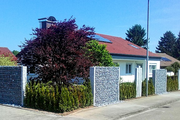 Haus mit Zaun und Steinwänden als SIchtschutz.